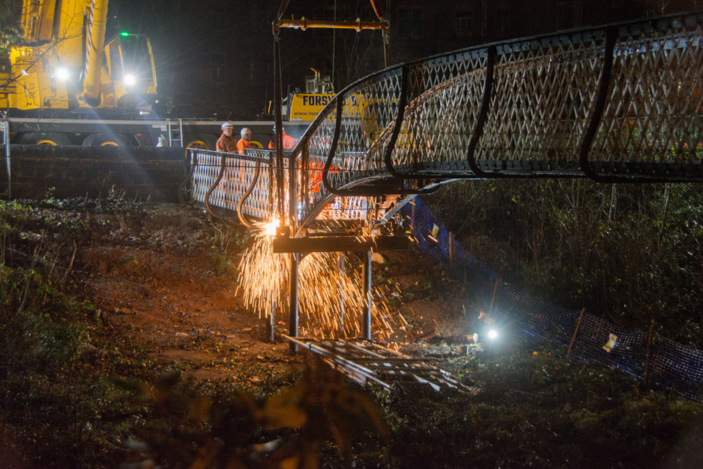 Sparks flying in the dark as workers use an acetylene torch on the bridge
